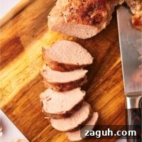 Sliced and cooked pork tenderloin on a wood cutting board.
