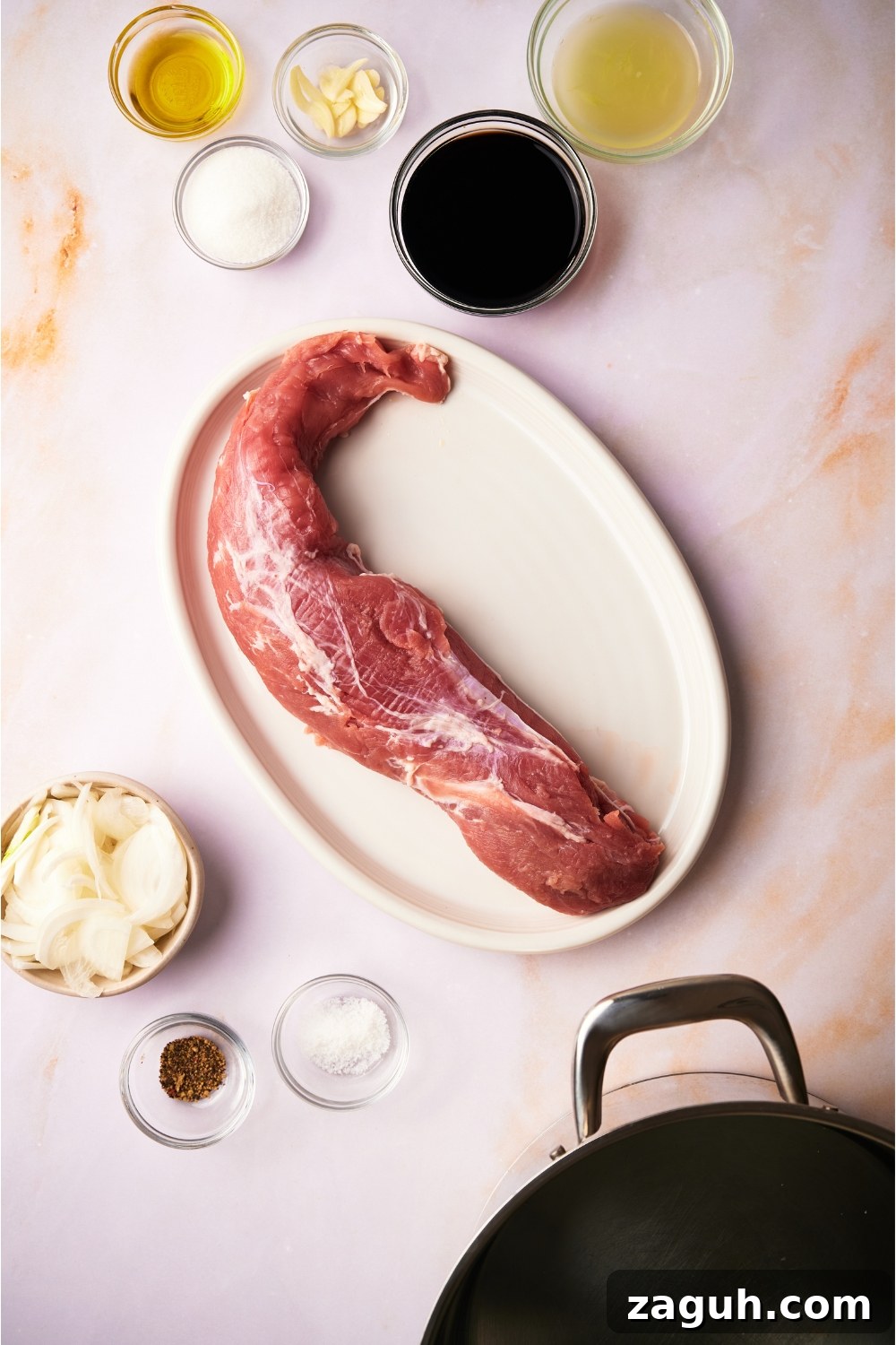 Juicy Sous Vide Pork Tenderloin Recipe — Perfectly Cooked Every Time 4 An assortment of ingredients including a plate of raw pork tenderloin and bowls of soy sauce, garlic, onion, sugar, and lemon juice.