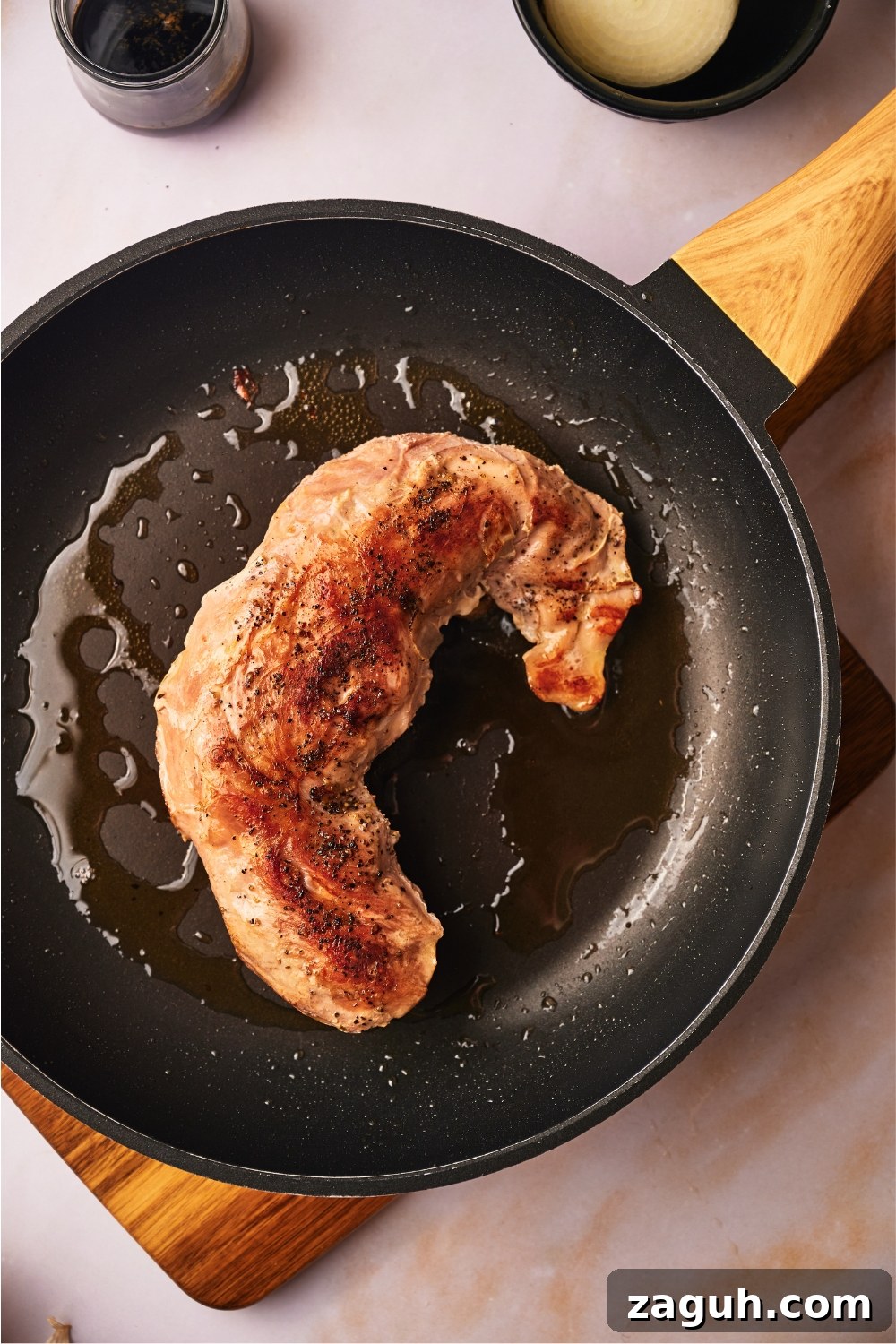 Juicy Sous Vide Pork Tenderloin Recipe — Perfectly Cooked Every Time 8 A cooked pork tenderloin being seared in a black skillet.