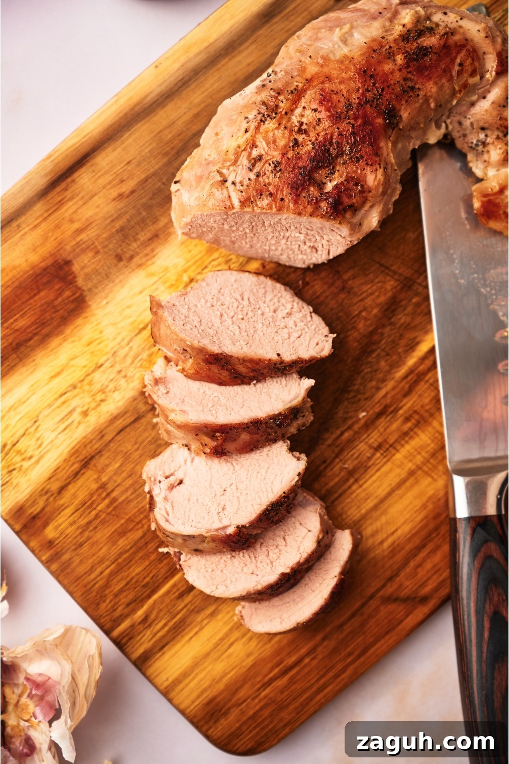 Juicy Sous Vide Pork Tenderloin Recipe — Perfectly Cooked Every Time 9 Sliced and cooked pork tenderloin on a wood cutting board.