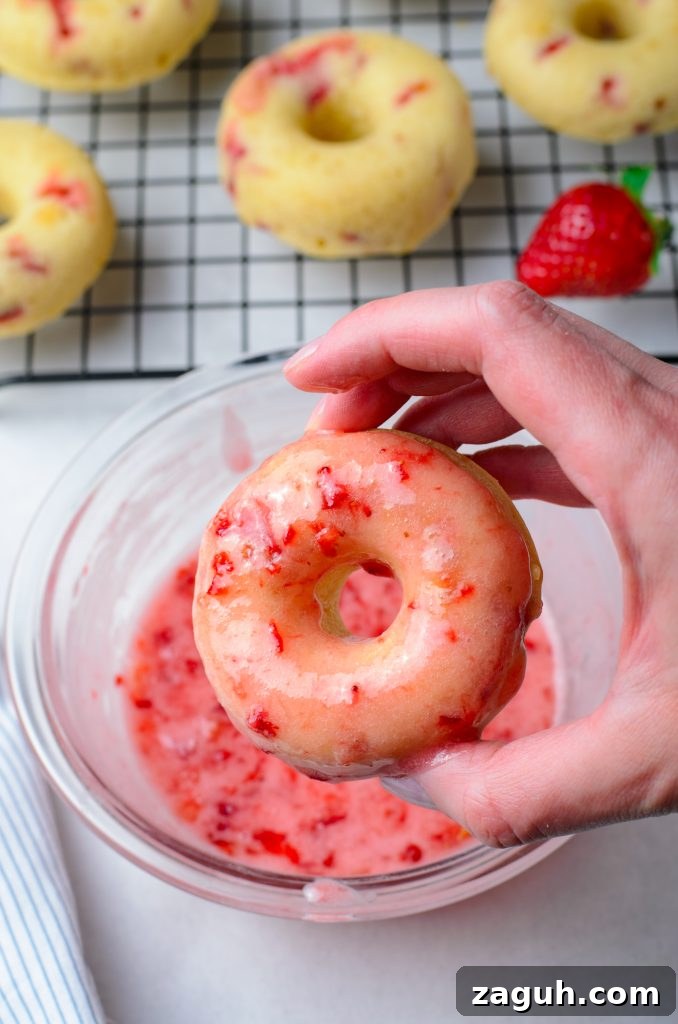 Strawberry-Glazed Baked Donuts: Light, Fruity Recipe 8 a hand holding up a freshly glazed strawberry donut