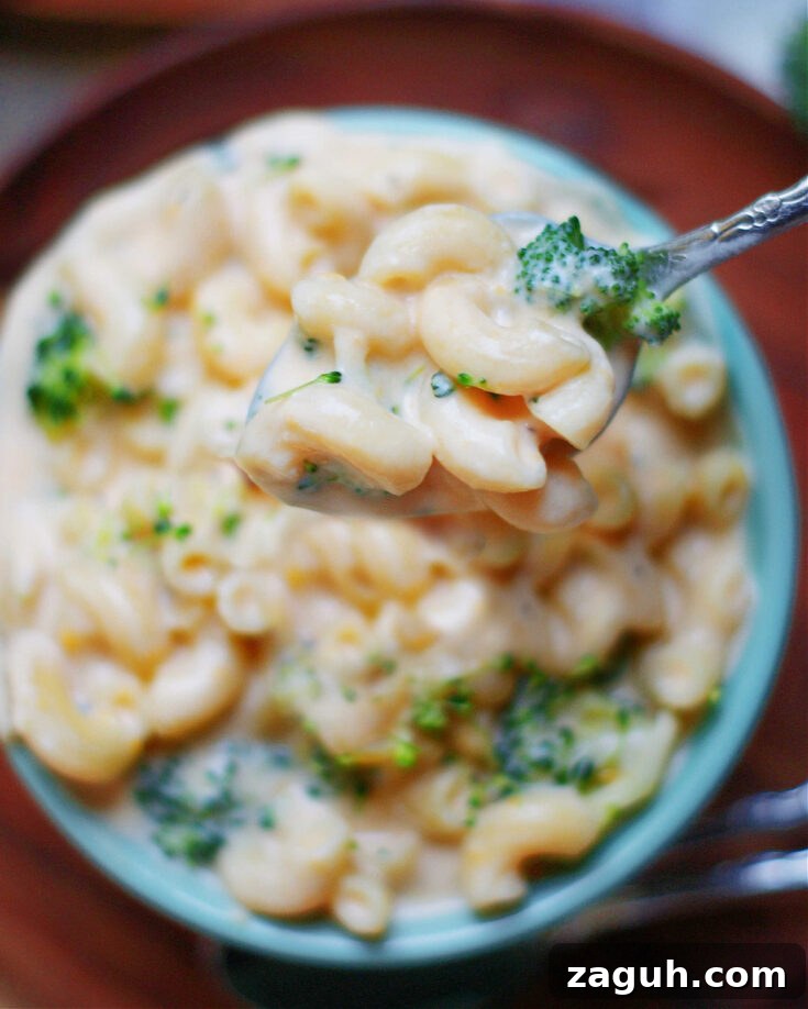 creamy broccoli macaroni and cheese in a bowl with spoon to show cheese sauce, pasta and broccoli