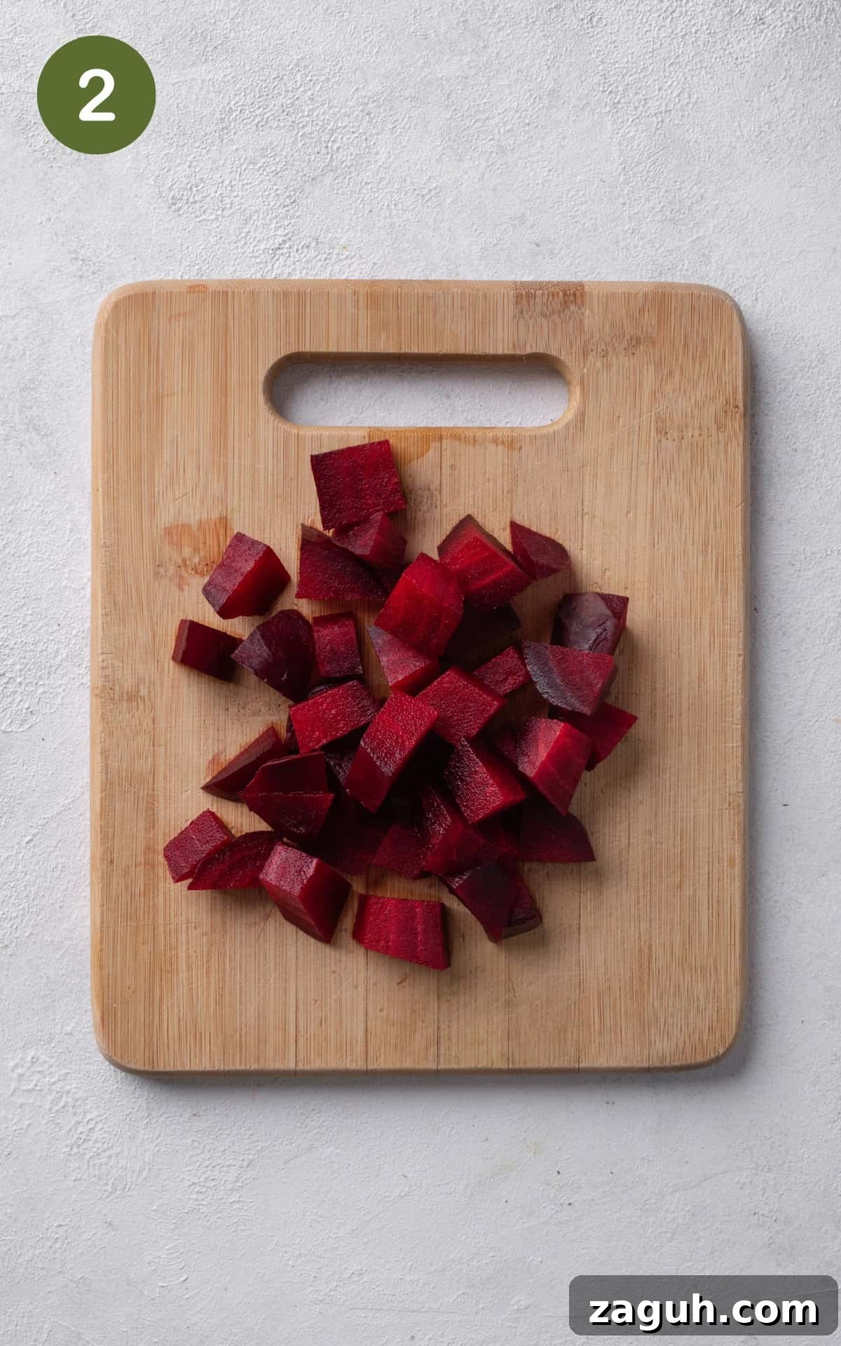 Creamy Beet Hummus Recipe with Garlic and Lemon 5 pieces of beet on a wooden cutting board.
