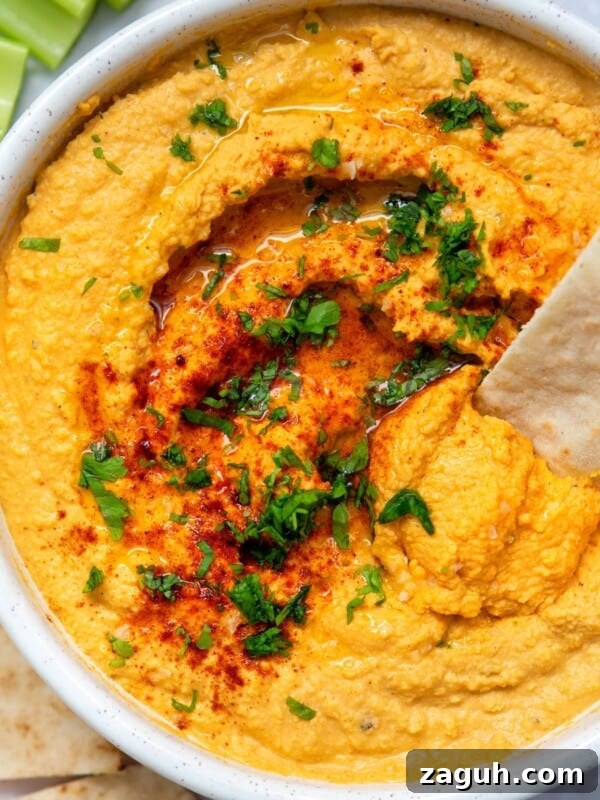 Creamy Beet Hummus Recipe with Garlic and Lemon 9 garlic hummus served in a white bowl with pitta and herbs.