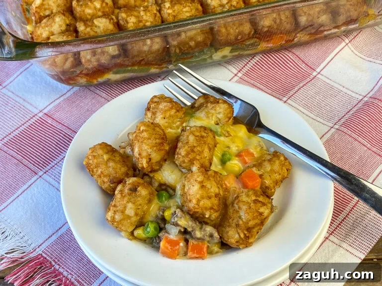 Cheesy Hamburger and Tater Tot Casserole Recipe That Families Love 2 Overhead view of tater tots on cream of chicken mushroom soup, peas, carrots, green beans and corn with hamburger on a plate with a fork