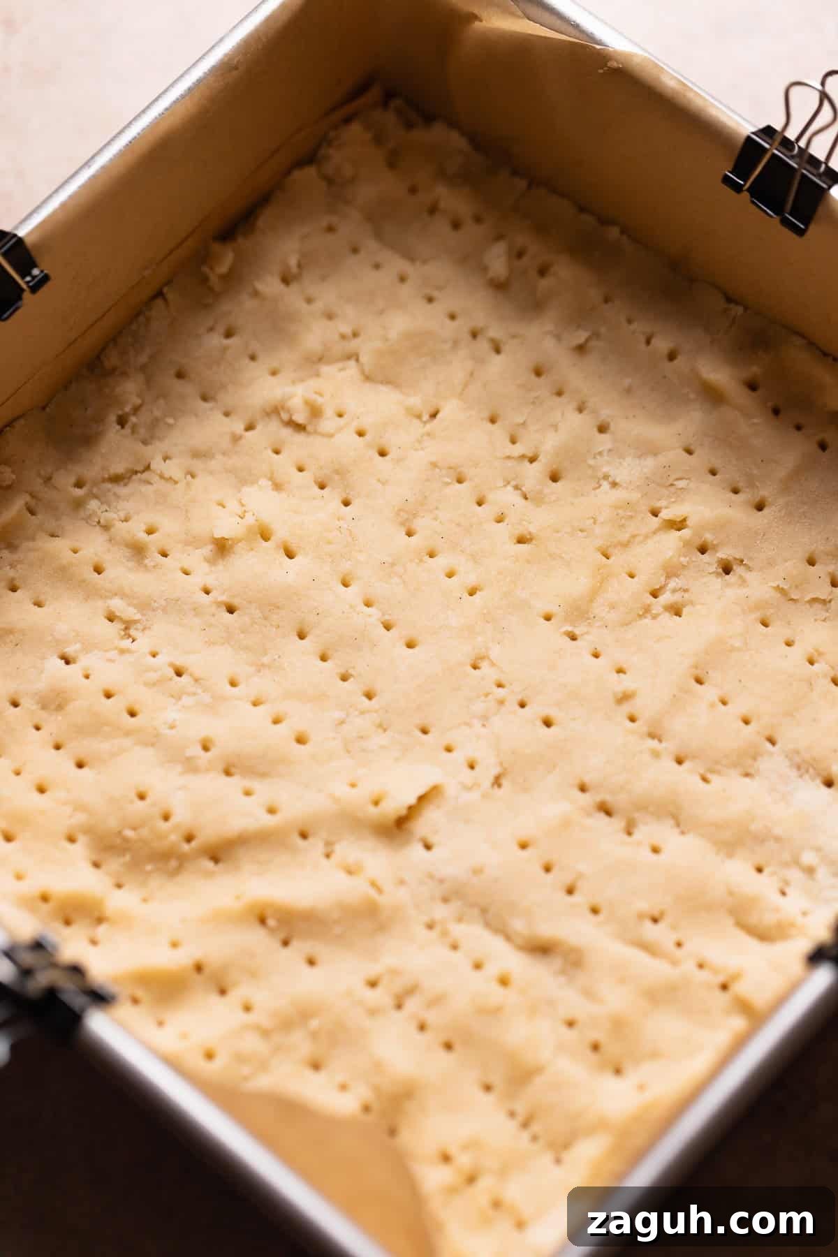 Tangy Lemon Bars with Buttery Shortbread Crust 4 Shortbread dough pressed into a square pan pricked with a fork before baking.