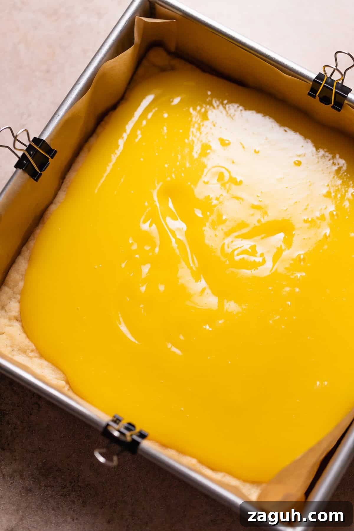 Tangy Lemon Bars with Buttery Shortbread Crust 7 Lemon curd being spread over the top of the baked shortbread crust.