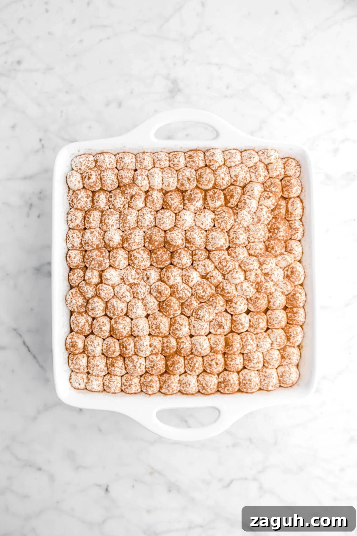 Authentic Italian Tiramisu Recipe: Step-by-Step Classic Guide 11 cocoa powder sifted over piped chantilly cream in white casserole
