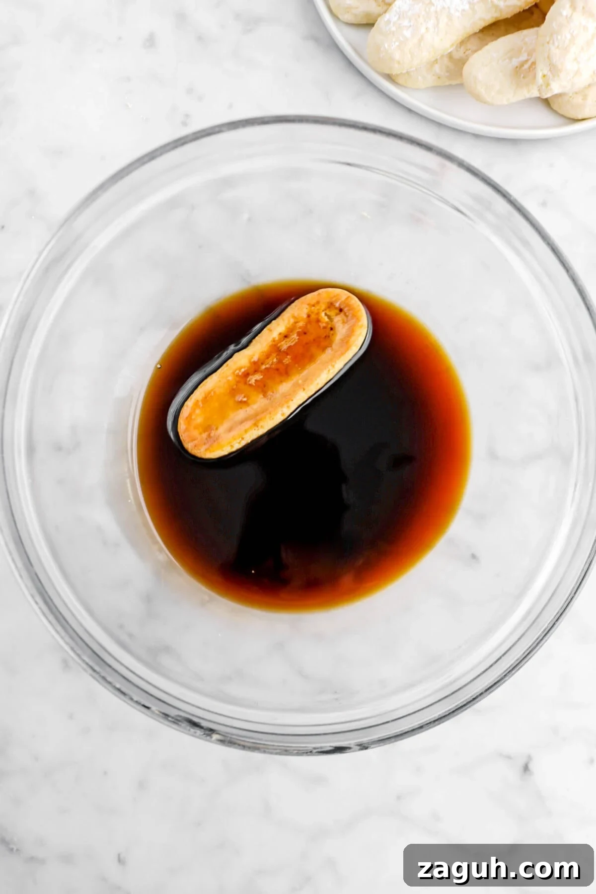 Authentic Italian Tiramisu Recipe: Step-by-Step Classic Guide 9 soaked ladyfinger in coffee mixture in glass bowl.