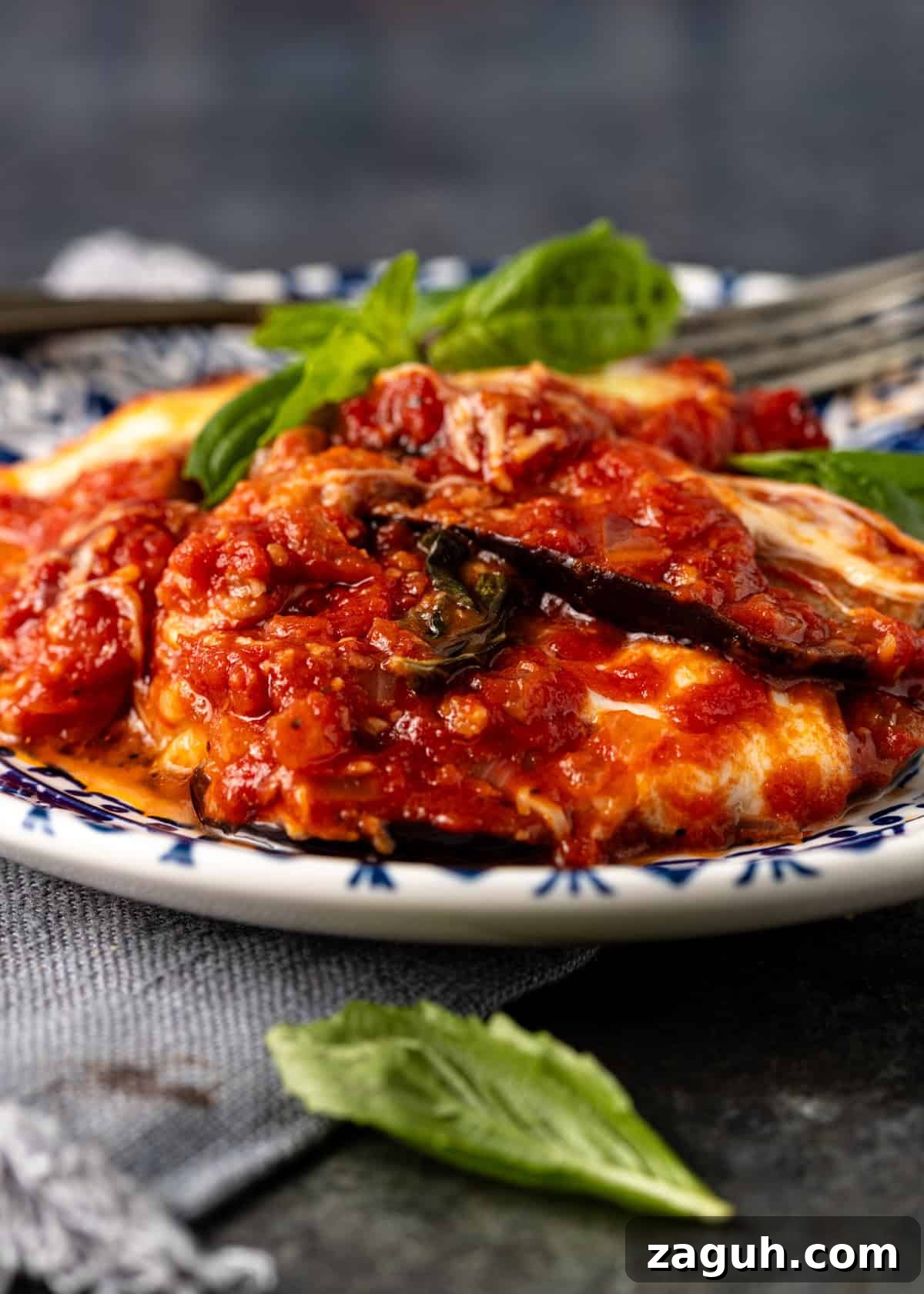 Classic Eggplant Parmigiana Recipe: Authentic Italian Parmigiana di Melanzane 15 closeup side view: eggplant parmigiana on white and blue plate ready to eat