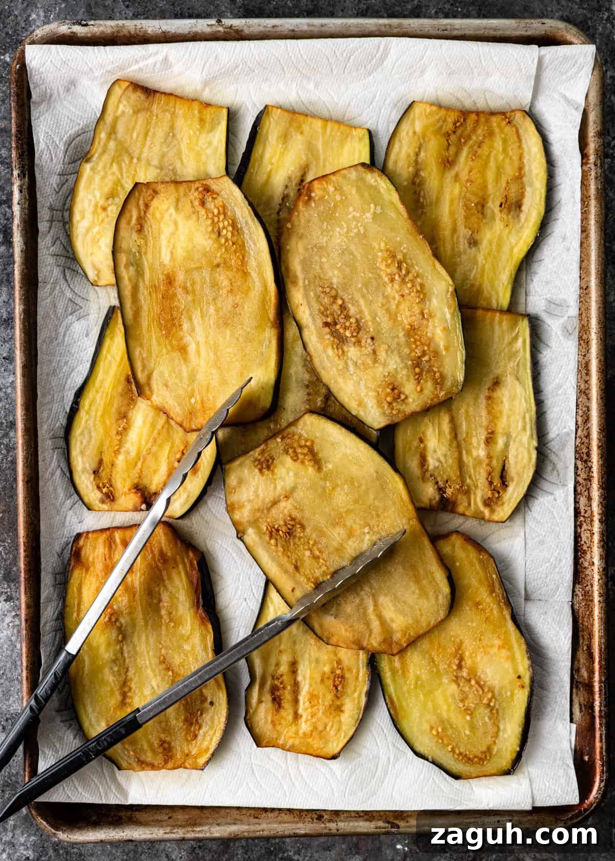 Classic Eggplant Parmigiana Recipe: Authentic Italian Parmigiana di Melanzane 8 overhead process shot: fried eggplant on baking sheet with tongs on top
