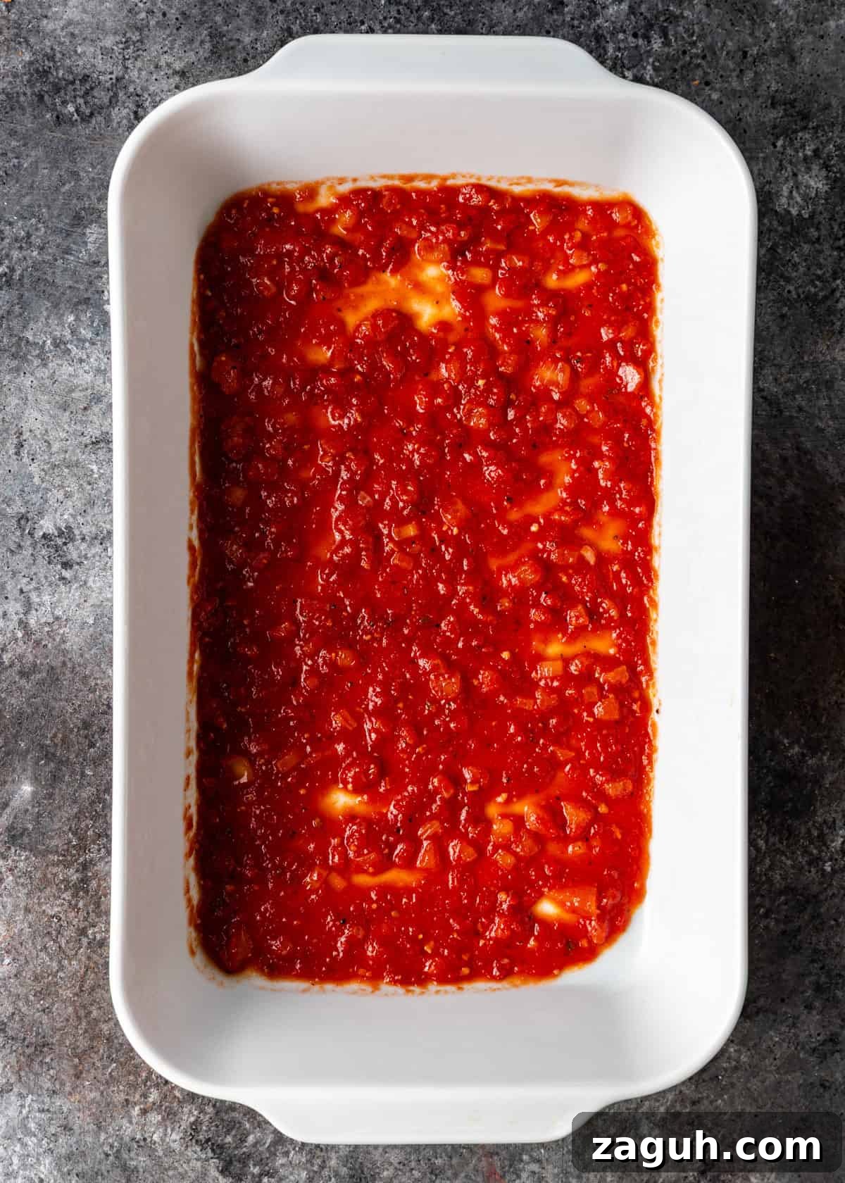 Classic Eggplant Parmigiana Recipe: Authentic Italian Parmigiana di Melanzane 9 overhead process shot: white baking dish with sauce in bottom