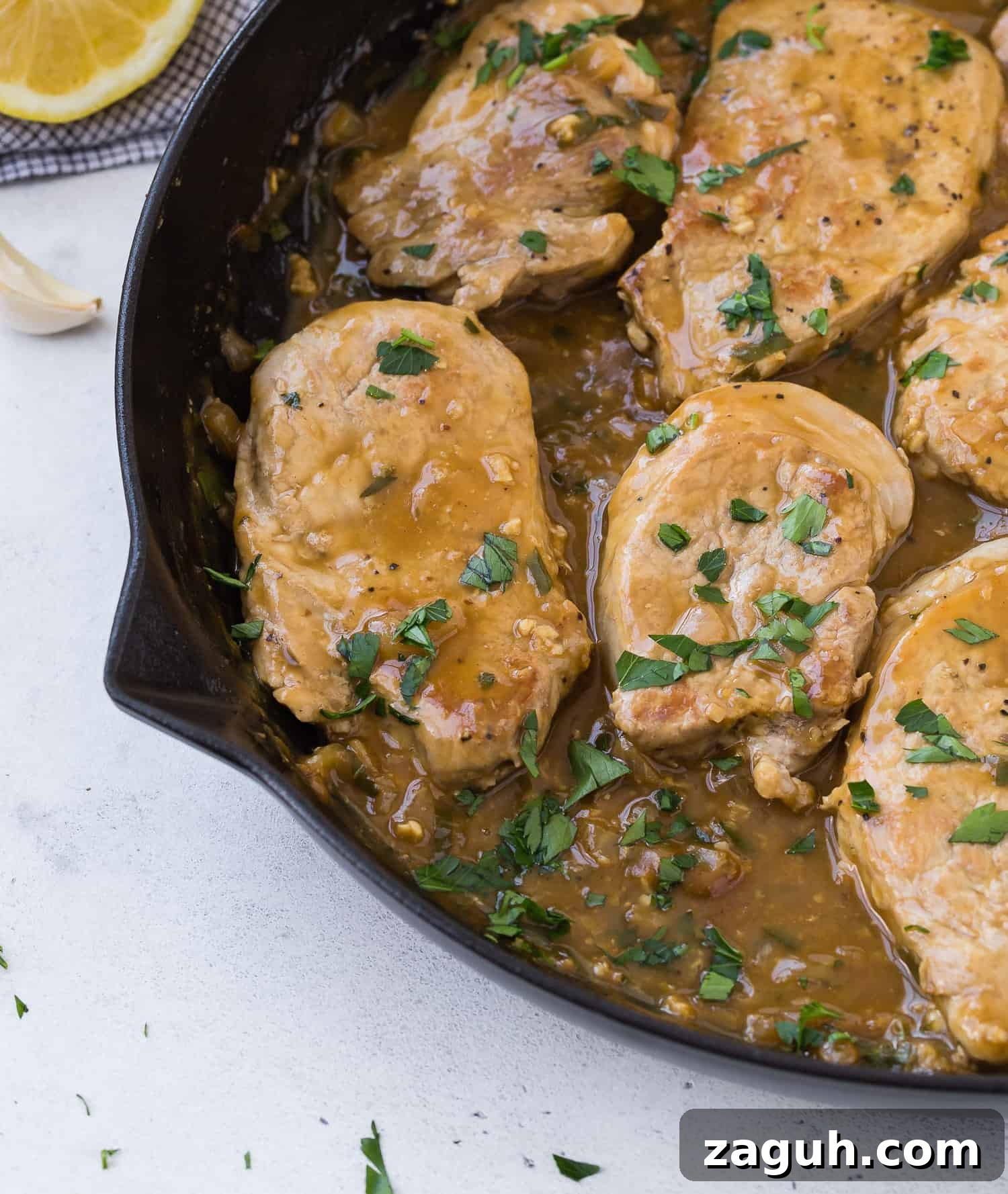 Lemon Garlic Pork Medallions with Creamy Pan Sauce 6 Pork in black skillet, with sauce, garnished with parsley.