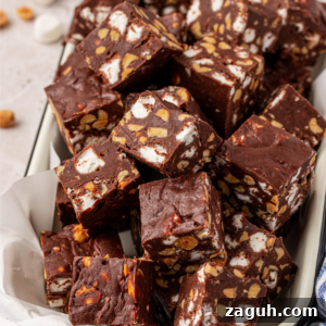 A tray filled with chocolate rocky road squares, showing chunks of marshmallows and peanuts mixed into the chocolate.