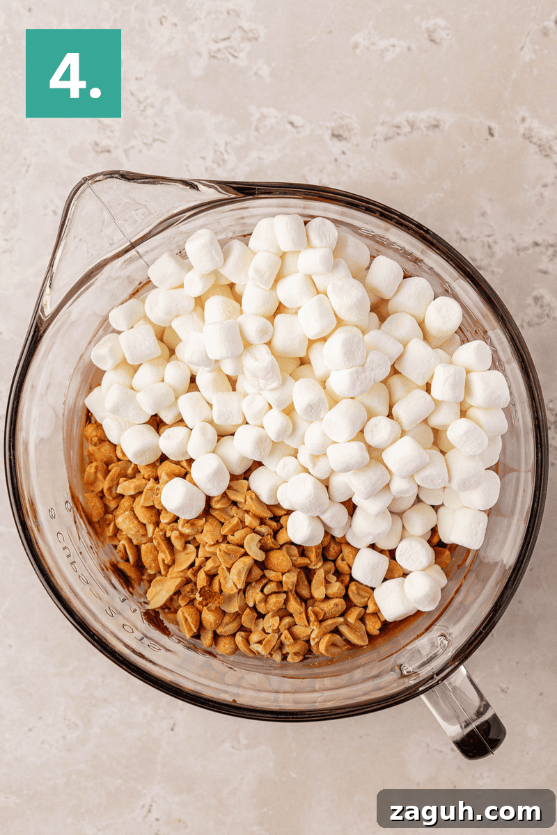 A glass mixing bowl filled with mini marshmallows and chopped peanuts sits on a light-colored countertop. A green square with the number 4 is in the top left corner.