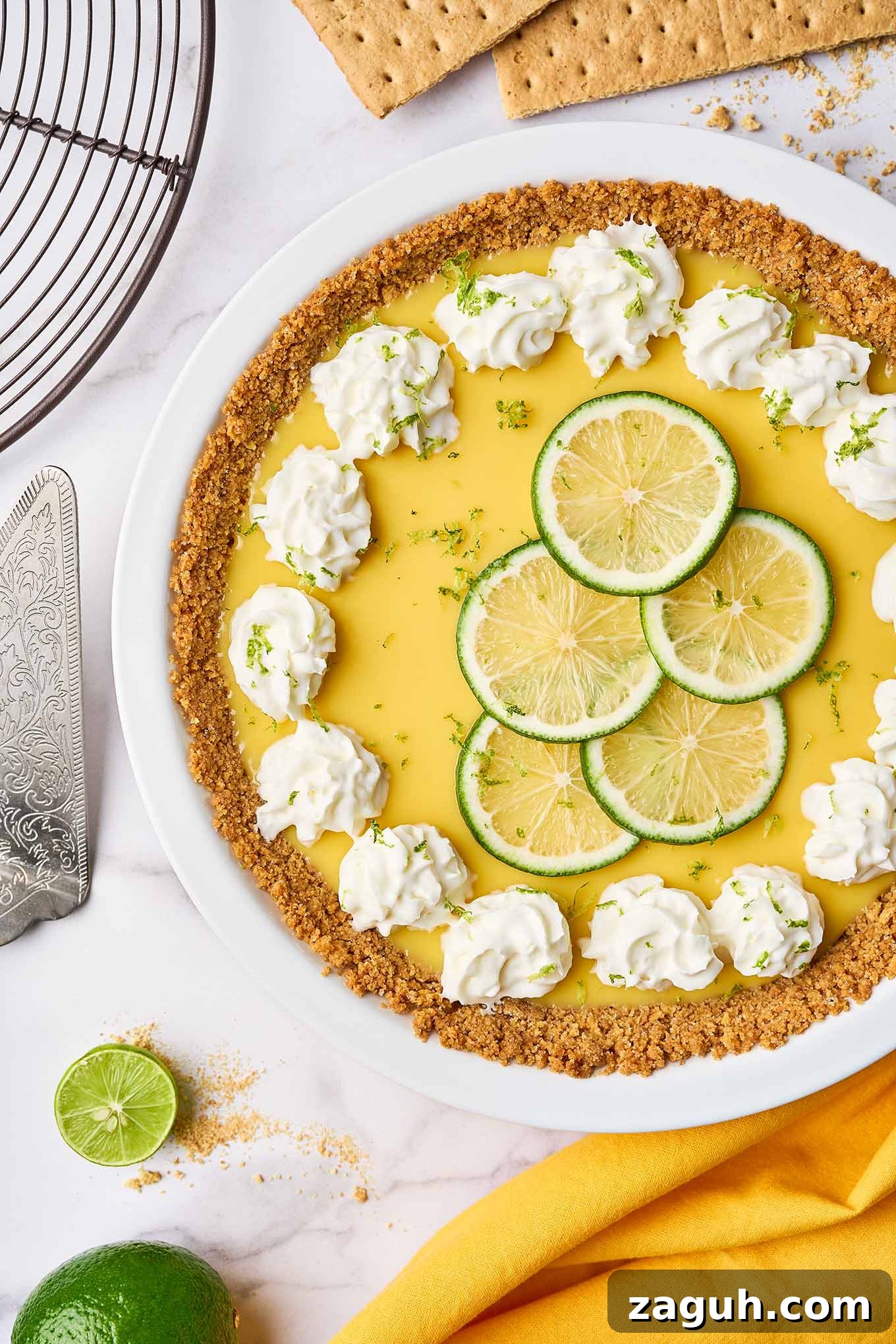 Florida Key lime pie with graham cracker crust, topped with whipped cream and lime slices in a white pie plate.