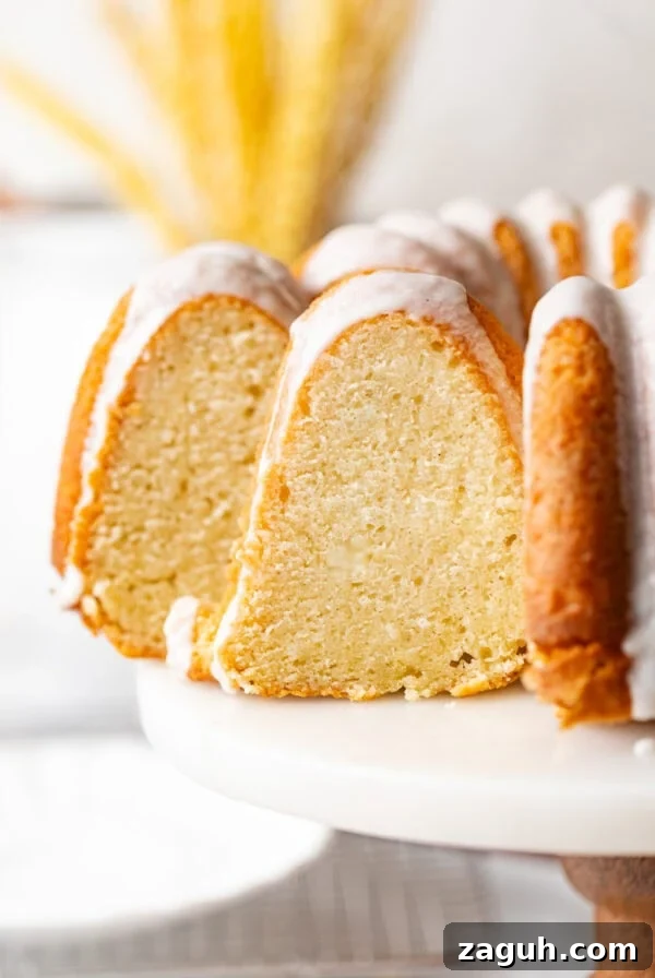 Moist Corn Pound Cake Recipe with Creamy Cornmeal Crumble 12 sliced sour cream pound cake on a cake stand topped with vanilla glaze.
