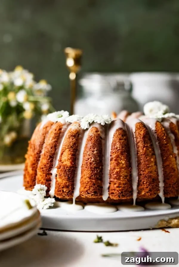 Moist Corn Pound Cake Recipe with Creamy Cornmeal Crumble 15 vanilla pound cake on a cake plate topped with vanilla glaze and edible flowers.