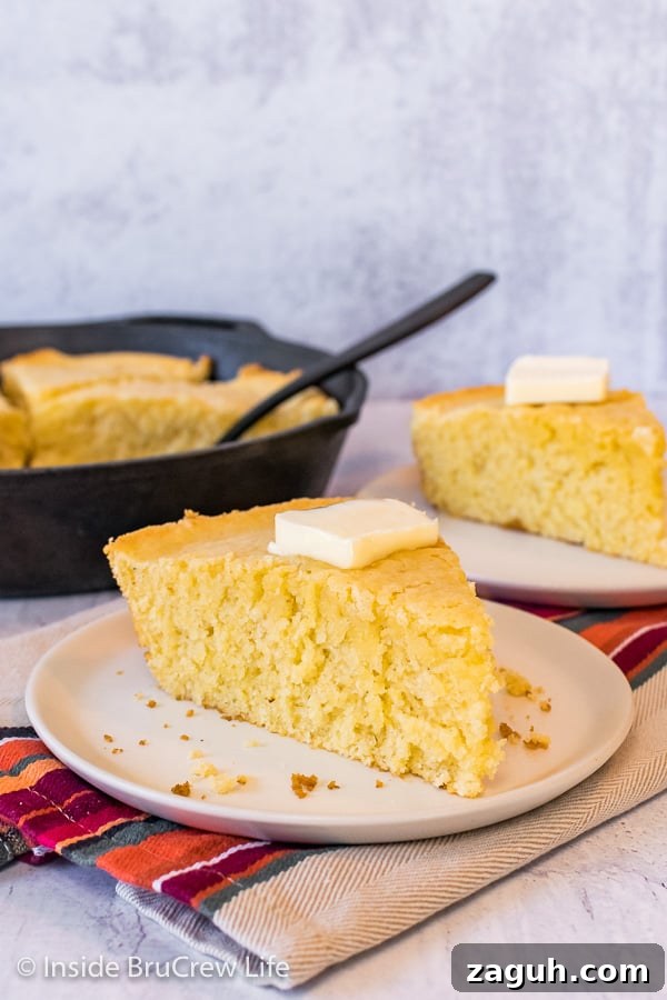 Easy Skillet Cornbread - cornbread is easy to make with ingredients from your pantry. Great recipe to make and serve with chili, pork, or soups. A wedge of easy cornbread on an off white plate with a skillet of cornbread behind it
