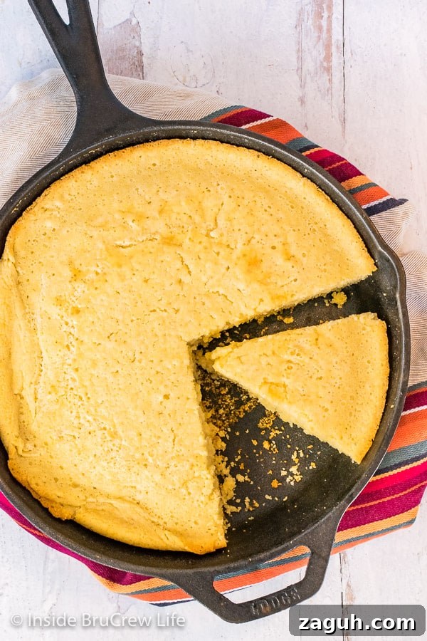 Easy Skillet Cornbread - a pan of cornbread is easy to make with simple ingredients from your pantry. Great recipe to make and serve with chili, pork, or soups. Overhead close up picture of a cast iron skillet with easy cornbread with a wedge cut in it