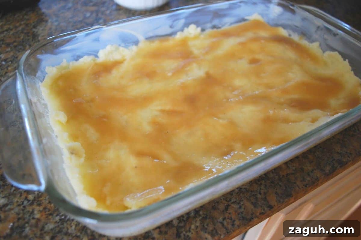 Ultimate Thanksgiving Casserole: One-Pan Holiday Dinner Recipe 6 mashed potatoes with gravy in a casserole dish.