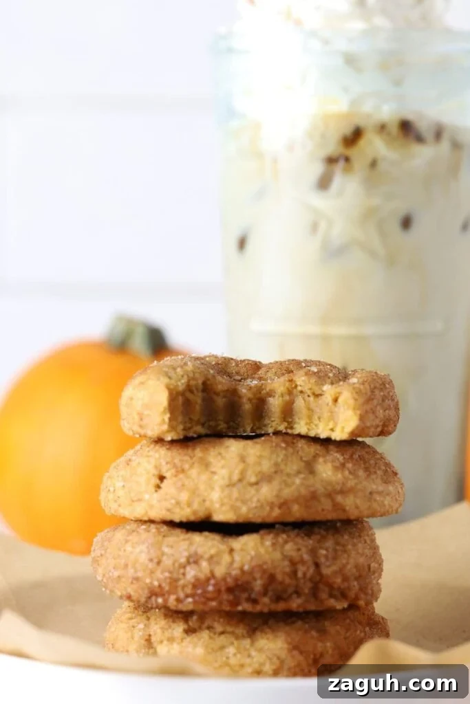 Sourdough Pumpkin Snickerdoodles: Spiced Autumn Cookies Recipe 3 Four sourdough pumpkin snickerdoodle cookies stacked on parchment paper with a coffee drink in background.