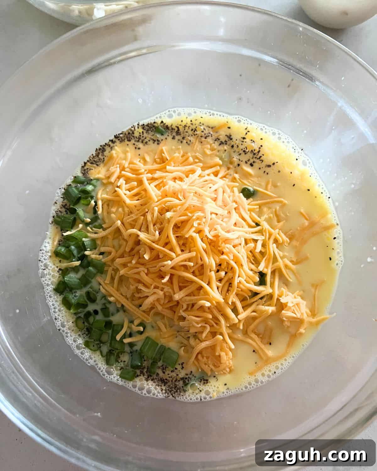 Paula Deen’s Cheesy Hash Brown Quiche Recipe 5 Eggs and hash brown quiche ingredients together in a bowl.