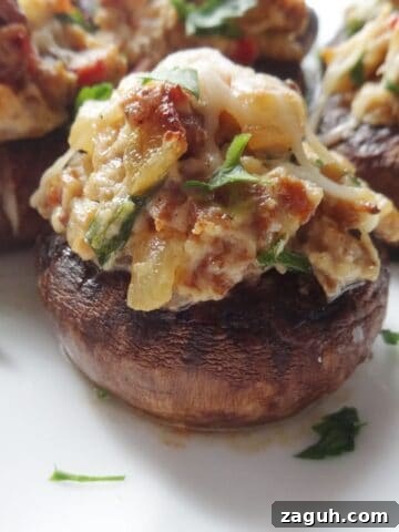 Cooked mushroom stuffed with sausage, onion, and cheese on plate.