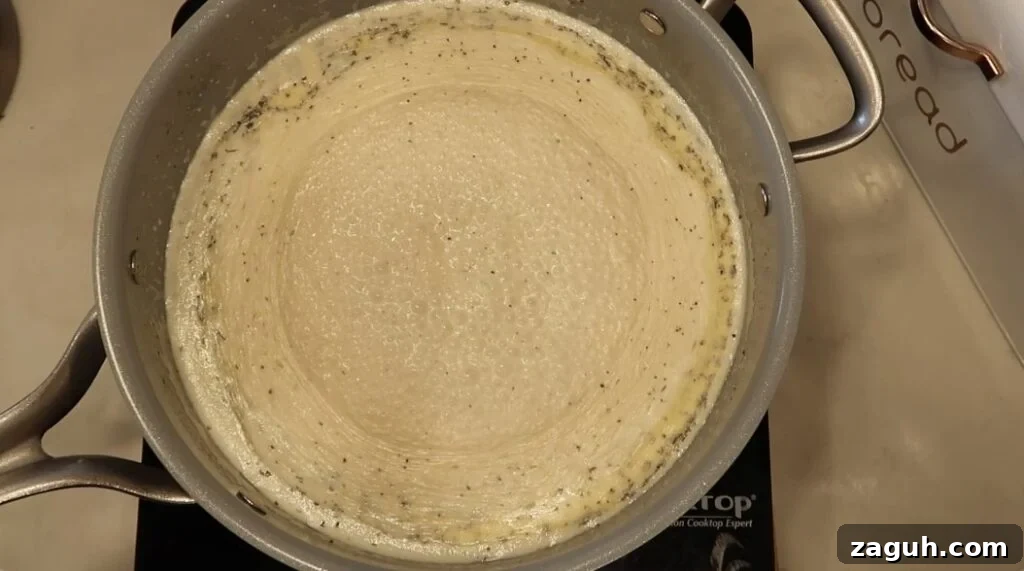 Creamy Garlic Sauce Recipe for Pasta, Chicken, and Veggies 13 Sauce simmering and thickening in pan