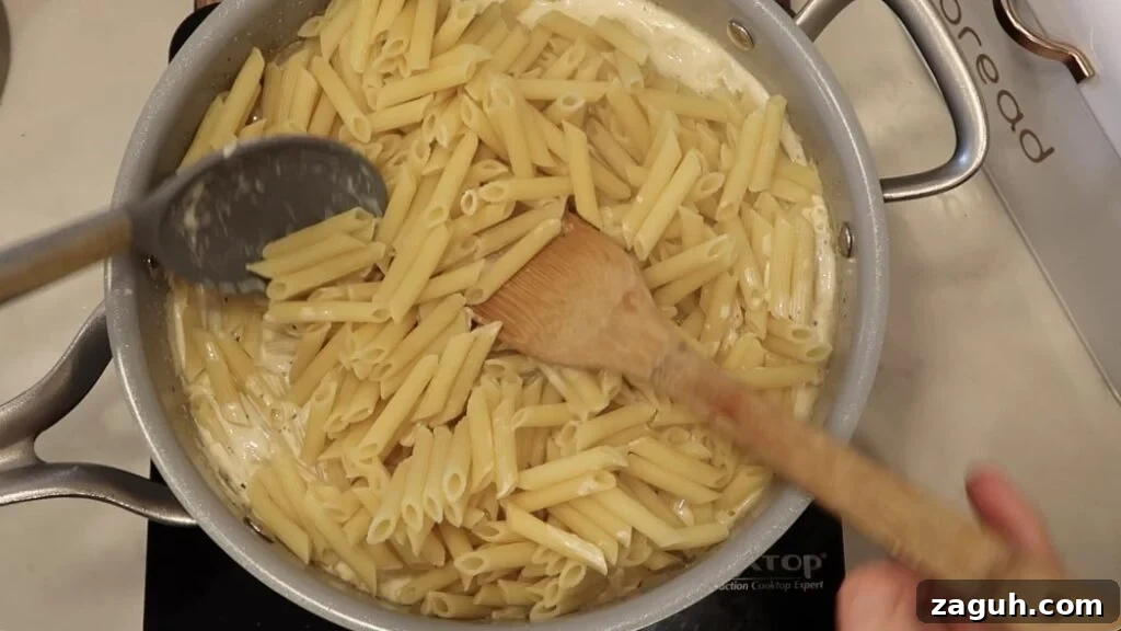 Creamy Garlic Sauce Recipe for Pasta, Chicken, and Veggies 16 Tossing pasta with sauce