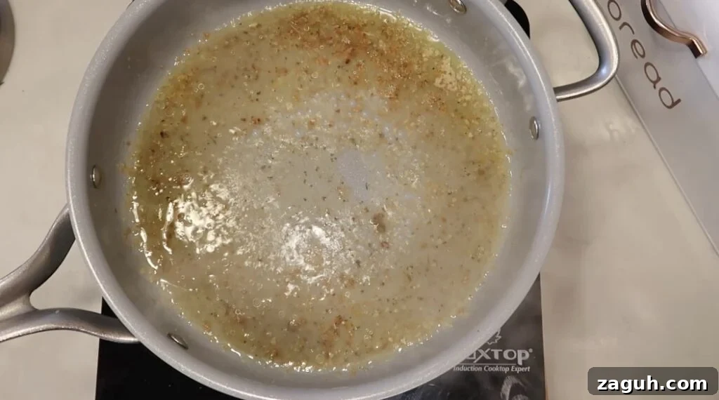 Creamy Garlic Sauce Recipe for Pasta, Chicken, and Veggies 8 Broth bubbling in pan