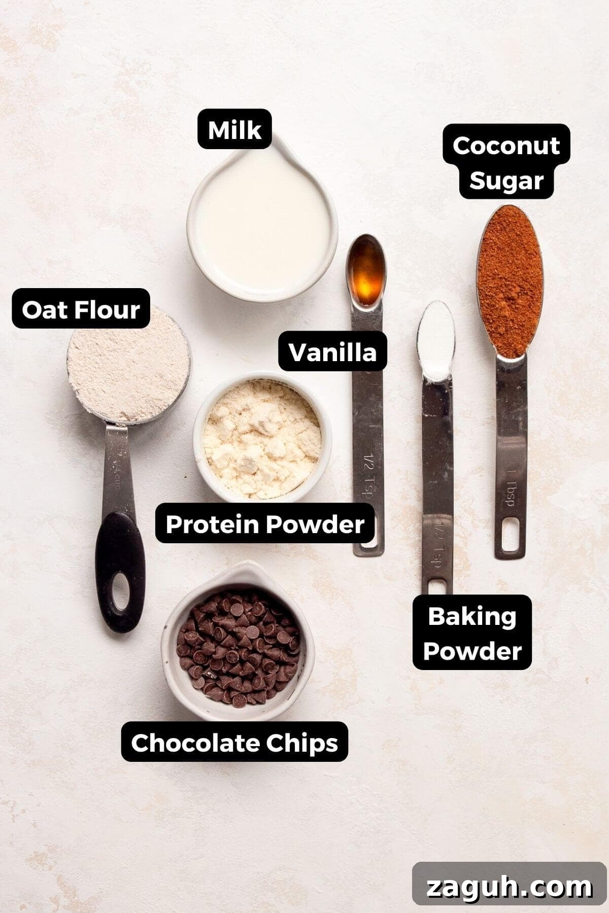 Protein Powder Mug Cake Recipe: Quick Single-Serve Treat 3 All ingredients in one minute protein mug cake recipe in small bowls including protein powder, oat flour, vanilla extract, coconut sugar, baking powder, milk, and chocolate chips.