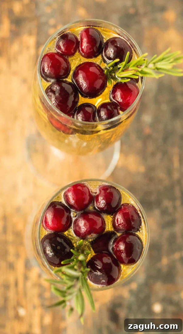 4 Fall Mimosa Recipes to Celebrate the Season 3 Two champagne flutes filled with white grape mimosas, topped with fresh cranberries and a sprig of rosemary.