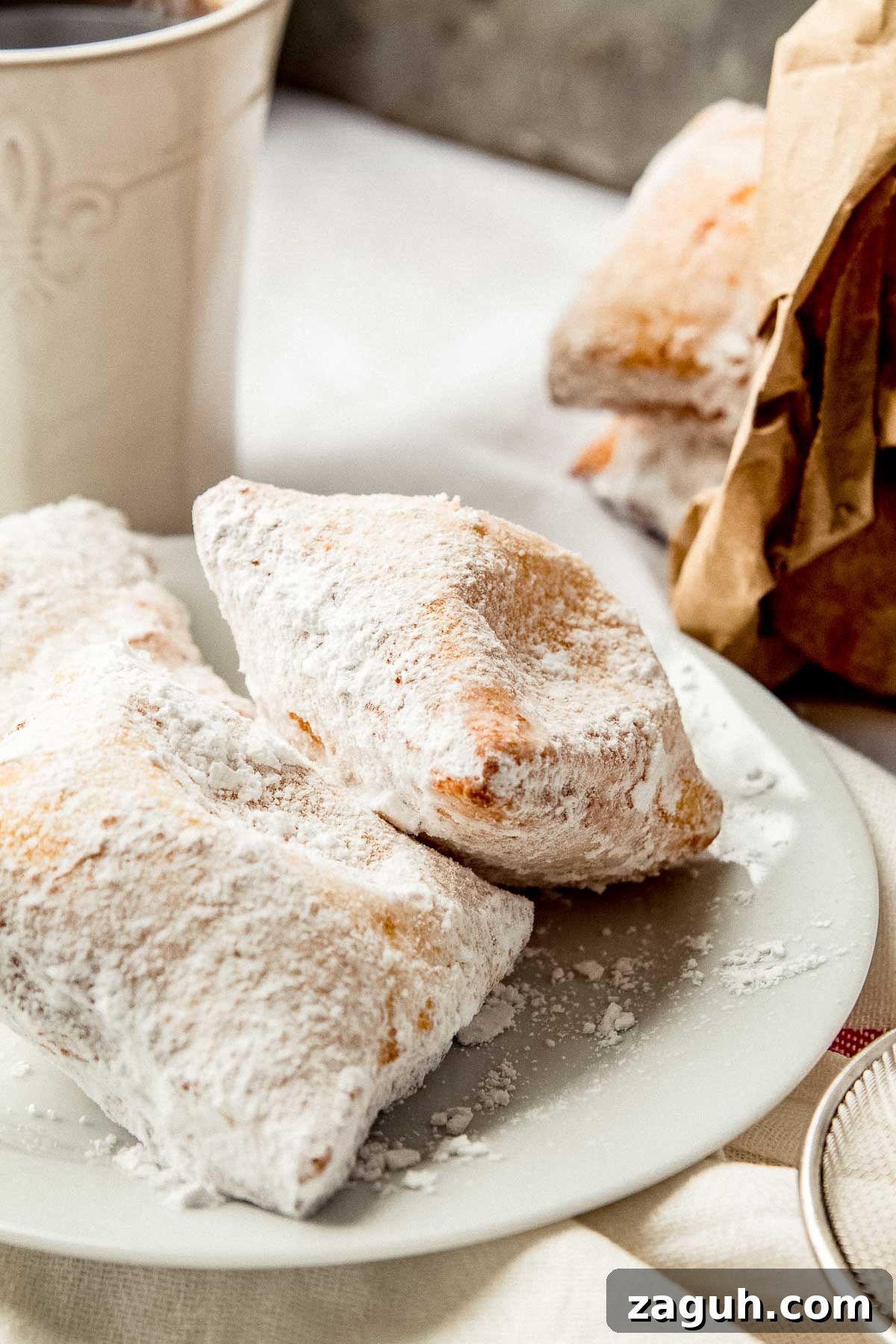 Beignets on a plate with a cup of coffee on the side.