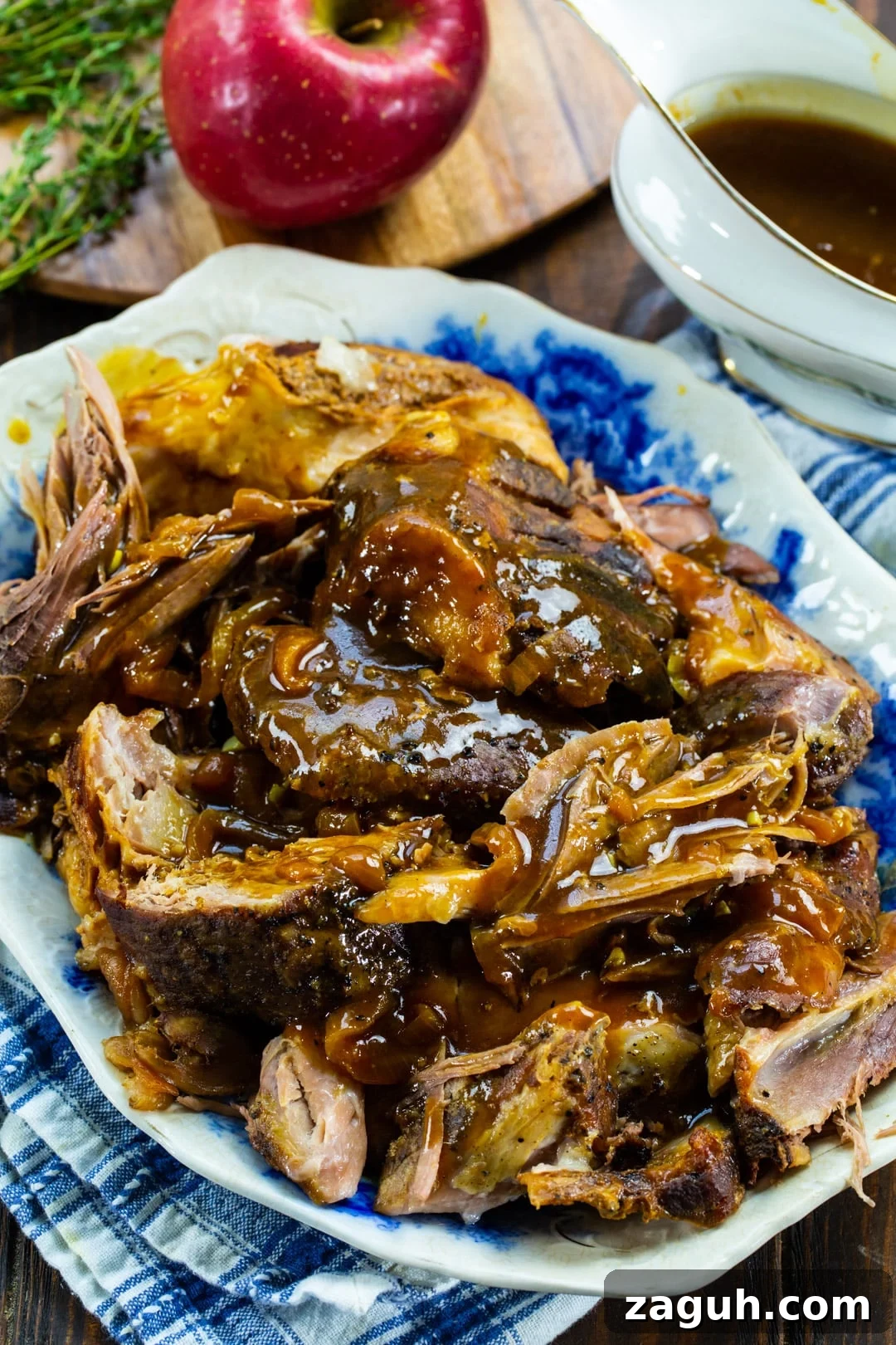 Slow Cooker Apple Cider Pulled Pork Recipe 3 Apple Cider Pork pulled into pieces with apple and gravy in background.