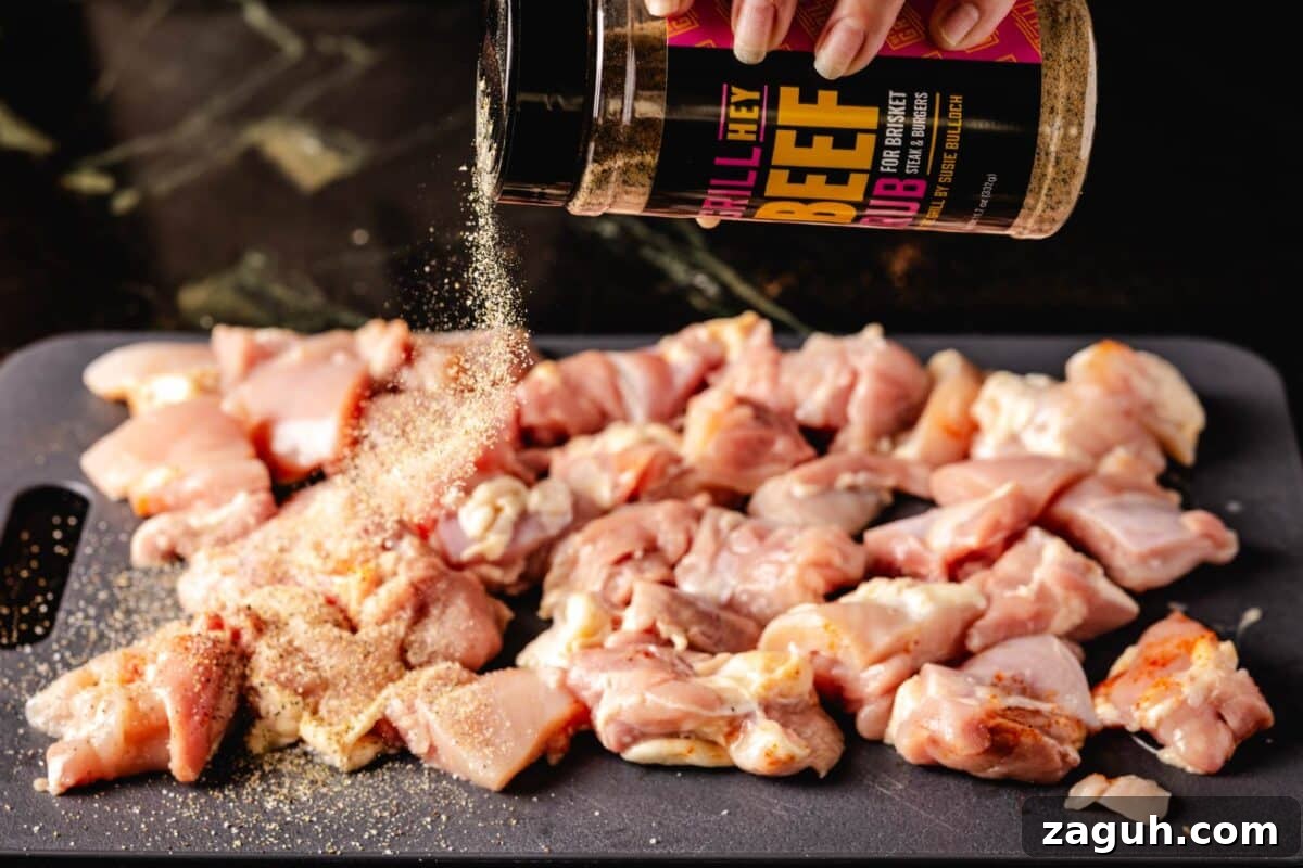 Grilled Buffalo Chicken Bites: Spicy BBQ Chicken Skewers 3 Chicken thighs on cutting board being seasoned with Beef Rub.