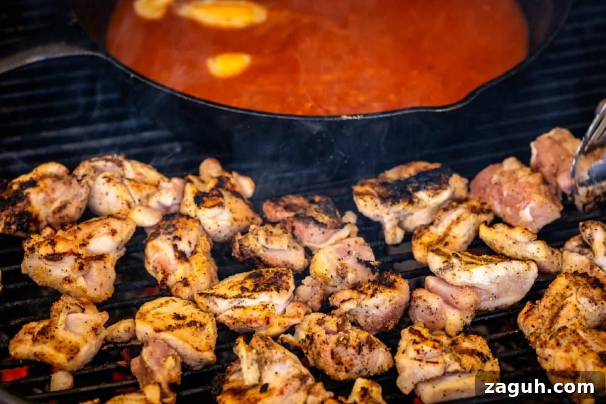 Grilled Buffalo Chicken Bites: Spicy BBQ Chicken Skewers 5 Grilled chicken thighs next to skillet of sauce.