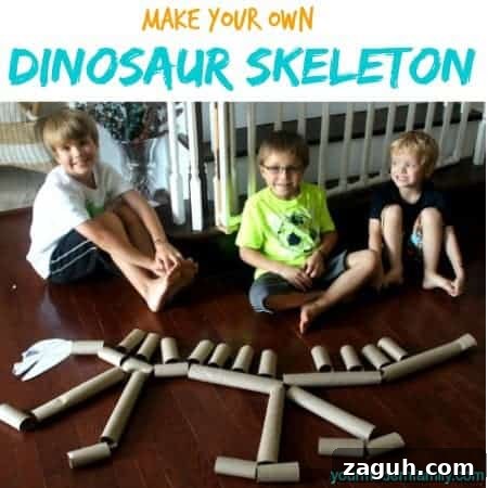 A group of kids posing for the camera in front of a dinosaur made of paper towel rolls.