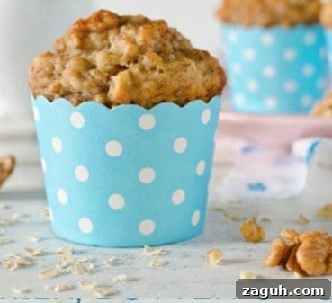 A blue and white polka dotted cup holding a banana muffin.