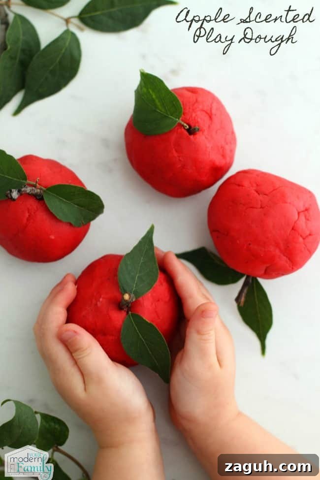 A close up of a hands holding red play dough apple craft.