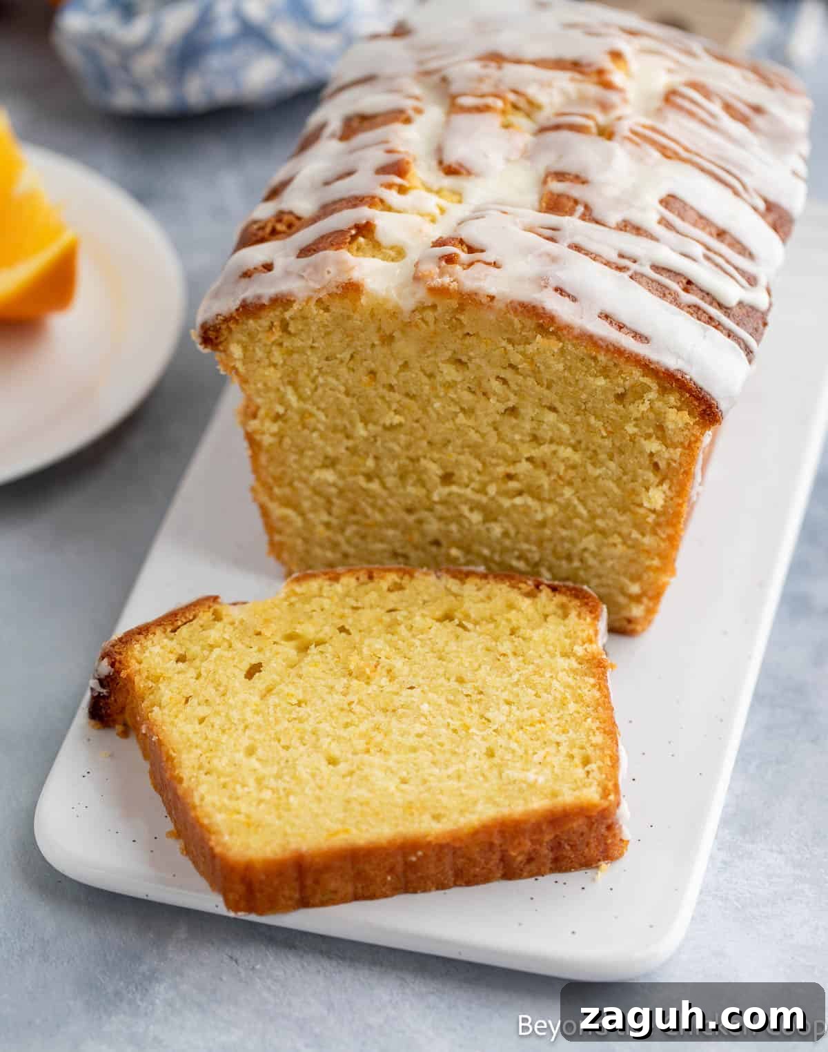 Moist Orange Pound Cake Recipe with Zesty Citrus Glaze 12 A slice of pound cake with an orange glaze on a platter.