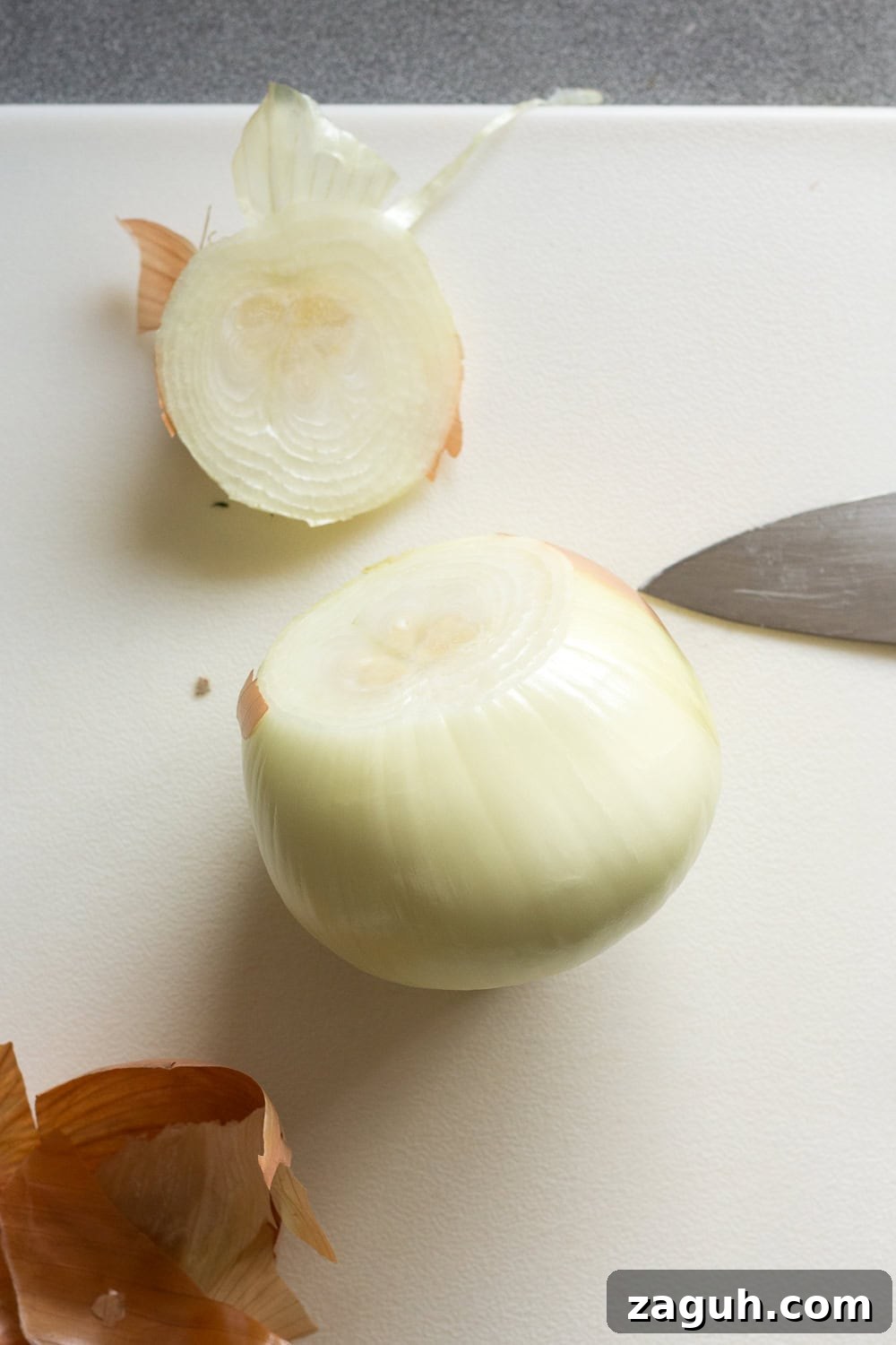 Grilled Onions Recipe: Whole30, Paleo & Gluten-Free Side Dish 3 An onion on a white cutting board with the top end cut off.