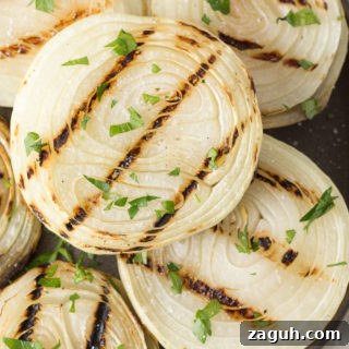 Grilled Onions Recipe: Whole30, Paleo & Gluten-Free Side Dish 10 Close up of grilled onions on a gray plate with chopped fresh herbs sprinkled on top.