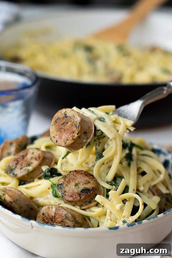 Quick Chicken Sausage Pesto Pasta with Spinach & Cherry Tomatoes 2 a fork lifting up a bite of creamy sausage pasta