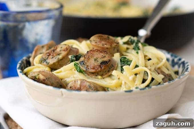 Quick Chicken Sausage Pesto Pasta with Spinach & Cherry Tomatoes 6 a bowl of creamy sausage pasta with a fork going in