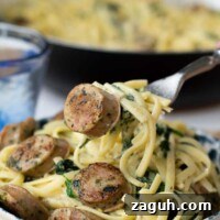 Quick Chicken Sausage Pesto Pasta with Spinach & Cherry Tomatoes 7 a fork lifting up a bite of creamy sausage pasta