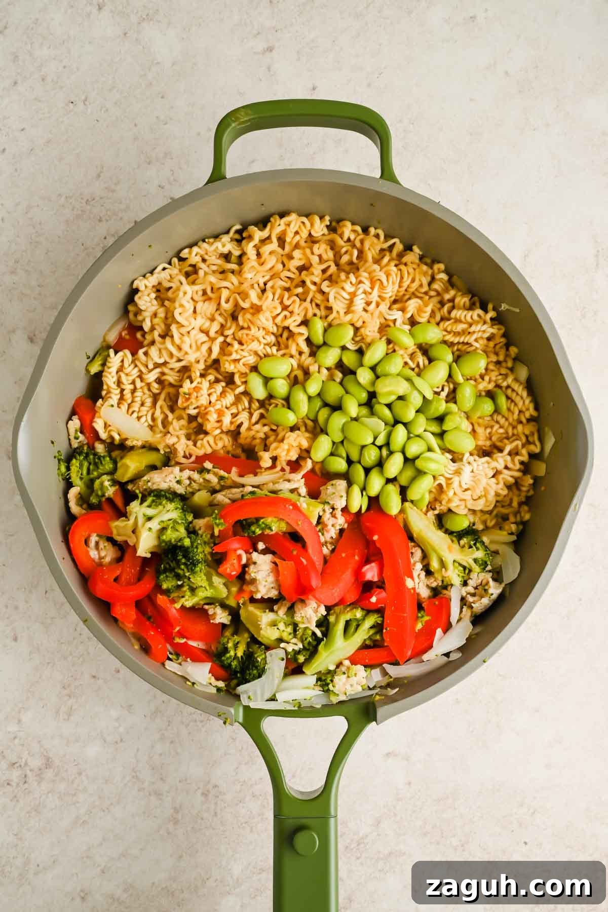 upgraded ramen with peppers, broccoli and edamame in green skillet.