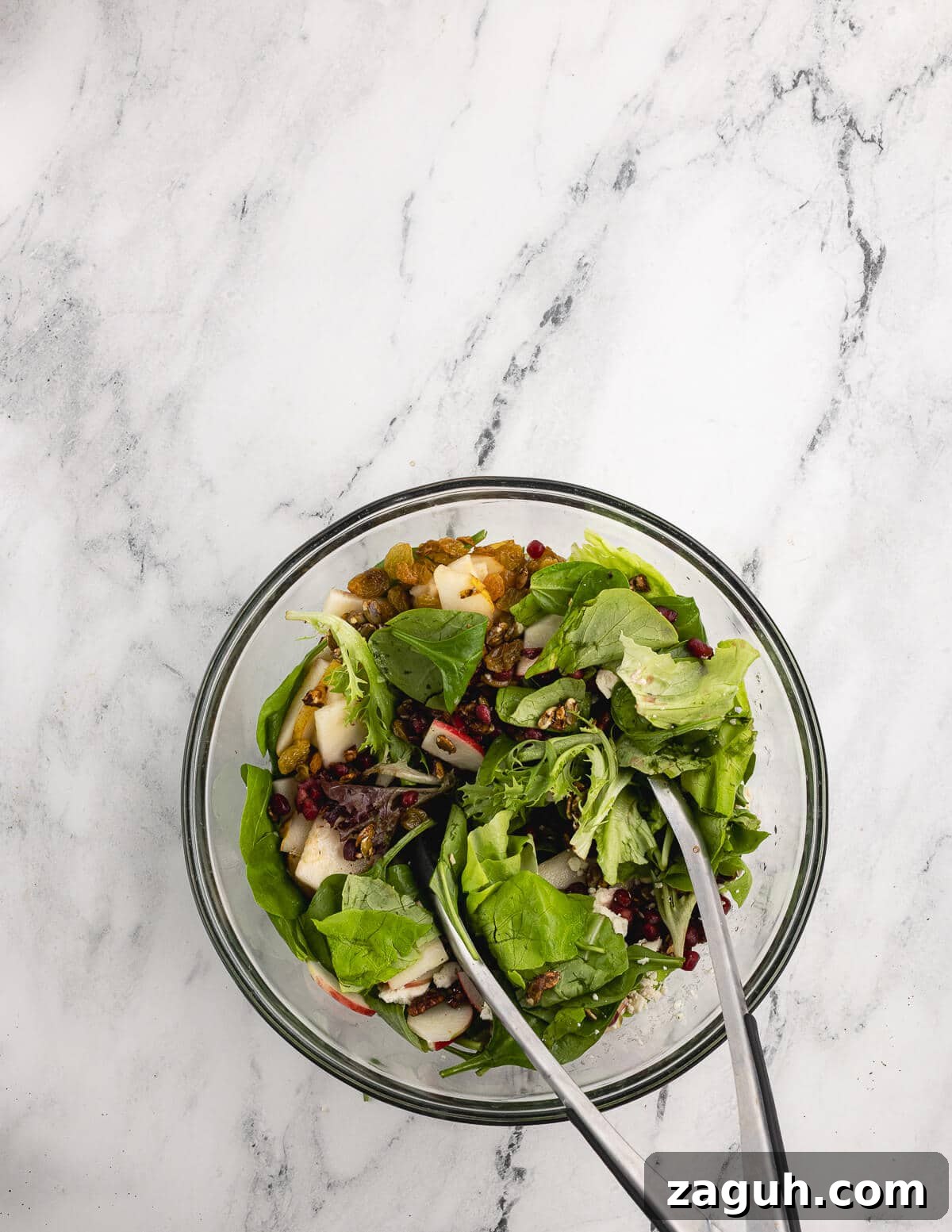Pomegranate, Pear & Candied Pepita Salad with Citrus Vinaigrette 11 tongs tossing mixed greens with mix-ins