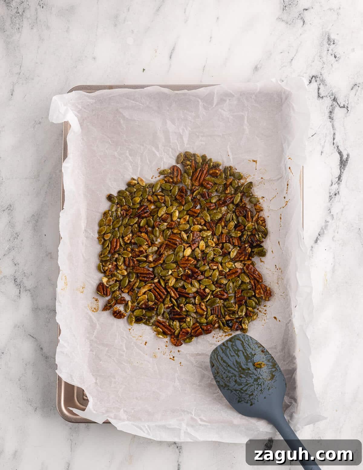Pomegranate, Pear & Candied Pepita Salad with Citrus Vinaigrette 5 pepitas and chopped pecans with maple syrup spread out on a sheet pan.