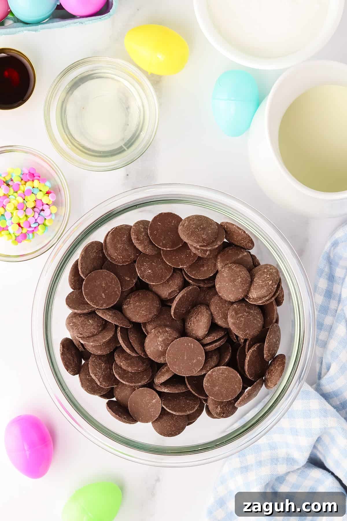How to Make Copycat Cadbury Creme Egg Candy at Home 4 Ingredients for Easter baking arranged on a kitchen counter, featuring a bowl of chocolate wafers at the center and the other ingredients around the bowl of chocolate